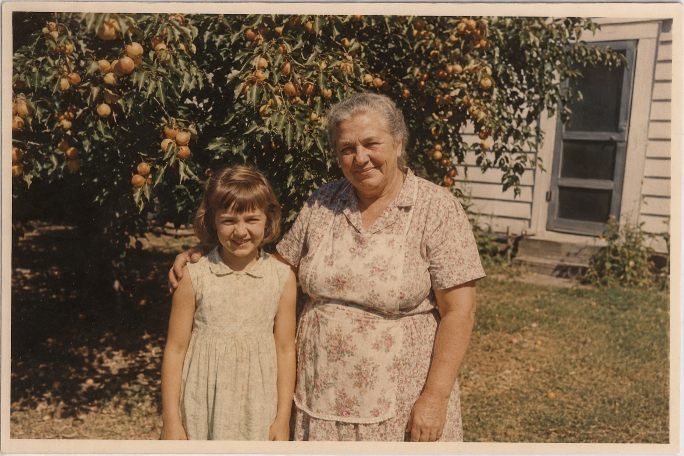 Eleanor as a girl, standing with her grandmother beside the apricot tree in the back garden.